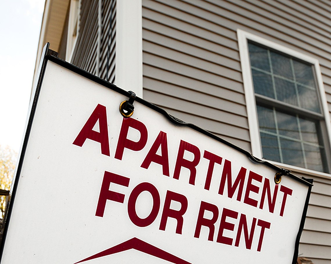 An apartment for rent sign outside a multifamily building